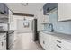 Bright kitchen features stainless steel appliances, farmhouse sink, stylish blue backsplash, and light wood floors at 5305 Allison St, Arvada, CO 80002