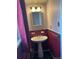 Unique bathroom with a pedestal sink, black tile floor, and eye-catching textured red wall at 1473 S Monaco S Pkwy, Denver, CO 80224