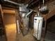 Basement utility area showcases furnace and water heater, with door leading to another room at 8319 Quivas Way, Denver, CO 80221