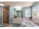 Bright bathroom with tiled walls, soaking tub, and glass-enclosed shower at 8888 S Dudley St, Littleton, CO 80128