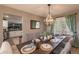 Formal dining room featuring a wooden table set for six, a decorative chandelier, and views into the kitchen at 8888 S Dudley St, Littleton, CO 80128
