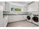 Modern laundry room boasts state-of-the-art washer/dryer, ample white cabinetry, and a window view at 14 S Grape St, Denver, CO 80246