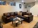 Spacious basement living area with a large sectional sofa, pillows, and glass coffee table at 9060 E Cherry Creek South Dr # E, Denver, CO 80231
