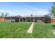 Spacious backyard with lush green lawn, brick home, and a quaint pathway at 1568 S Dudley Ct, Lakewood, CO 80232