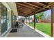 Inviting covered patio with wood ceiling, seating, and view of the landscaped backyard at 1568 S Dudley Ct, Lakewood, CO 80232