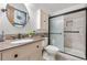 Modern bathroom offers a sleek vanity with bronze hardware, tiled shower with glass door, and a decorative mirror at 16308 E Wyoming Dr, Aurora, CO 80017
