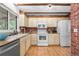 Bright kitchen featuring white appliances, vintage cabinets, and a brick backsplash at 16308 E Wyoming Dr, Aurora, CO 80017