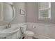 Stylish powder room with a pedestal sink, wainscoting, and decorative mirror at 11796 Edenfeld St, Parker, CO 80134