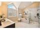 Modern bathroom features a soaking tub, glass-enclosed shower, double vanity, and a large arched window with privacy shutters at 9407 Dolton Way, Highlands Ranch, CO 80126