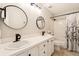 Bathroom with double sinks, circular mirrors, and a shower and tub with a patterned curtain at 9407 Dolton Way, Highlands Ranch, CO 80126