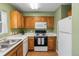 Well-lit kitchen with oak cabinets, white appliances, ample counter space, and view of the sink and window at 1457 S Pierce St, Lakewood, CO 80232