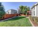 Spacious backyard with a large grassy area, wood fence, landscaping, and a pergola-covered patio at 16553 Gilpin St, Thornton, CO 80602