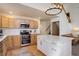 Beautiful kitchen featuring stainless appliances, island with white countertop, hardwood floors, and a view of the stairs at 16553 Gilpin St, Thornton, CO 80602