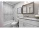 Modern bathroom featuring a tub with tile surround, granite vanity, and decorative mirror at 7155 E Exposition Ave, Denver, CO 80224
