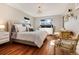 Sunlit bedroom features hardwood floors, a statement chandelier, and a plush bed with many pillows at 7155 E Exposition Ave, Denver, CO 80224