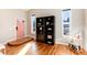 Inviting entryway featuring a pink front door, hardwood floors, and a dark wood bookshelf with stylish decor at 7155 E Exposition Ave, Denver, CO 80224