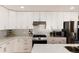 Modern kitchen featuring stainless steel appliances, quartz countertop, stylish backsplash, and white cabinetry at 7155 E Exposition Ave, Denver, CO 80224