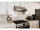 Modern kitchen featuring stainless steel appliances, quartz countertops, stylish backsplash, and white cabinetry at 7155 E Exposition Ave, Denver, CO 80224