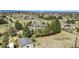 Aerial view of a suburban home surrounded by mature trees and lush greenery with mountain views in the distance at 7388 S Ireland Cir, Centennial, CO 80016