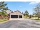 Detached two car garage with a black door, attached to the house with a fence and driveway at 7388 S Ireland Cir, Centennial, CO 80016