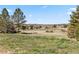 Expansive grassy field with a rustic antique tractor and mountain views in the background at 7388 S Ireland Cir, Centennial, CO 80016