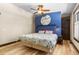 Bright bedroom features a unique blue accent wall, wood-trimmed windows, hardwood floors and stylish ceiling fan at 209 American Way, Breckenridge, CO 80424