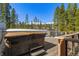 Back deck with a hot tub and views of the mountains, all surrounded by a beautiful pine forest at 209 American Way, Breckenridge, CO 80424