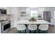 Bright kitchen featuring white cabinets, stainless steel appliances, marble backsplash, and a green island with seating at 6526 S Cherry Way, Centennial, CO 80121