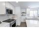 Bright kitchen featuring white cabinets, stainless steel appliances, marble backsplash, and a green island with seating at 6526 S Cherry Way, Centennial, CO 80121