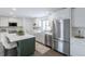 Bright kitchen featuring white cabinetry, stainless steel appliances, quartz counters, and a green island with seating at 6526 S Cherry Way, Centennial, CO 80121