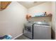 A functional laundry room equipped with a washer, dryer, and shelving at 9316 Harrison St, Thornton, CO 80229