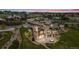 Aerial view of a luxurious home with a stone and stucco exterior, a spacious deck, and lush landscaping at dusk at 2466 Spruce Meadows Dr, Broomfield, CO 80023