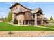 Stunning multi-story home with stone and stucco exterior, complemented by lush landscaping and a vibrant green lawn at 2466 Spruce Meadows Dr, Broomfield, CO 80023