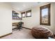 Well-lit office space with built-in shelves, a modern desk, and two windows offering natural light at 2466 Spruce Meadows Dr, Broomfield, CO 80023