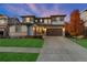 Dusk view of a home with manicured lawn, stone accents and an attached two-car garage at 515 Orion Ave, Erie, CO 80516