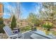 Backyard featuring a cozy patio setup with a blue chair and table, surrounded by lush greenery and a wooden fence at 19691 E 59Th Dr, Aurora, CO 80019