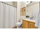 Well-lit bathroom featuring a shower with white curtain, toilet, and vanity with wood cabinets at 19691 E 59Th Dr, Aurora, CO 80019