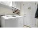 Practical laundry room with a white washer and dryer set, shelving, and access door at 19691 E 59Th Dr, Aurora, CO 80019