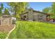 Charming home exterior with a brick chimney, manicured lawn, lush trees, and a storage shed, showcasing its curb appeal at 2473 S Carr Ct, Lakewood, CO 80227