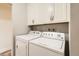 Bright laundry room featuring a washer, dryer, and white cabinets for storage at 2473 S Carr Ct, Lakewood, CO 80227