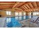 Indoor swimming pool with vaulted ceilings, wood beams, a jacuzzi, and lounge chairs at 8525 E 149Th Dr, Thornton, CO 80602