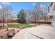 Landscaped backyard featuring a concrete patio, mature trees, and a privacy fence at 613 Rio Rancho Way, Brighton, CO 80601