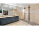 Bathroom featuring double sinks, pebble shower floor, and tiled shower with multiple shower heads at 613 Rio Rancho Way, Brighton, CO 80601