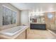 Bright bathroom with large window over garden tub, double sinks, and pebble-floor shower at 613 Rio Rancho Way, Brighton, CO 80601