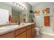 Bathroom featuring double sinks with tan countertop, wood cabinets, and decorative floral art at 7130 Simms St # 206, Arvada, CO 80004