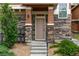 Charming front entrance with stone accents, a small porch, and well-maintained landscaping at 7130 Simms St # 206, Arvada, CO 80004