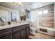 Bathroom with double sink, large mirror, shower and tub combo, and neutral tile and walls at 2305 Quitman St, Denver, CO 80212