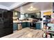 Kitchen with green cabinets, black backsplash, stainless steel appliances, and gray wood floors at 2852 W Ellsworth Ave, Denver, CO 80219