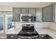 Close up of kitchen featuring stainless steel appliances, gray cabinets and white backsplash at 17476 E Bellewood Cir, Aurora, CO 80015