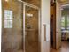 Bright walk-in shower with stone-look tile, glass doors, and view to bedroom and closet at 15179 W Washburn Ave, Lakewood, CO 80228